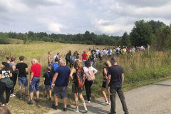 Polana, którą wędruje grupa ludzi w stronę lasu