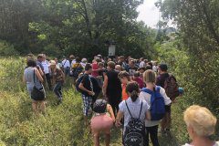 Grupa osób stojąca na polanie otoczonej lasem