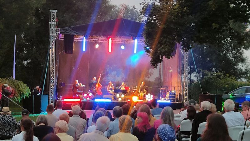 Scena plenerowa oraz zespół. Przed sceną widać grupę ludzi.