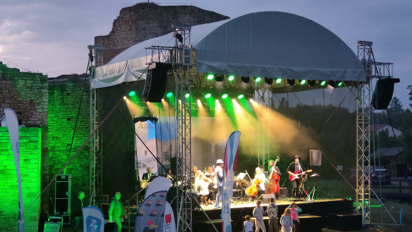 Na zdjęciu widać scenę ustawioną na tle zamku. Na scenie odbywa się koncert.